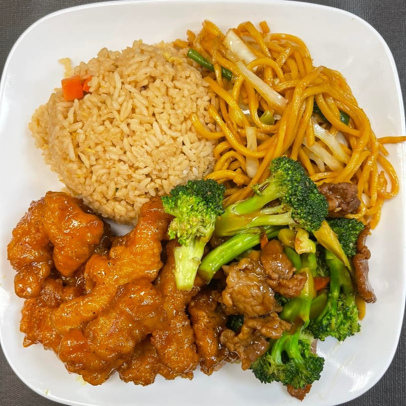 A white plate with Mr You Chinese Food's orange chicken, beef and broccoli, fried rice, and lo mein.