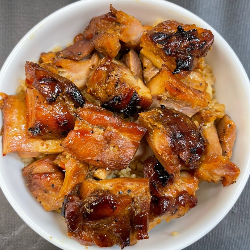 Close-up of Mr You Chinese Food's glistening, caramelized chicken pieces served over rice in a white bowl.