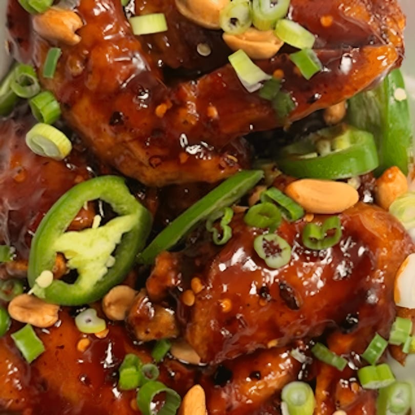 Close-up of Mr You Chinese Food's spicy chicken wings with jalapeños, peanuts, and green onions.